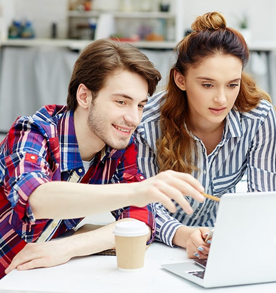 un homme et une femme entrain de regarde l'écran de leurs pc